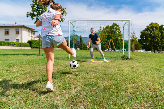 Father and daughter playing football on a meadow