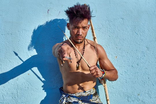 Tribal man with his traditional arch and arrows leaning on blue wall, Lubango, Angola