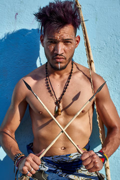 Tribal man with his traditional arch and arrows leaning on blue wall, Lubango, Angola