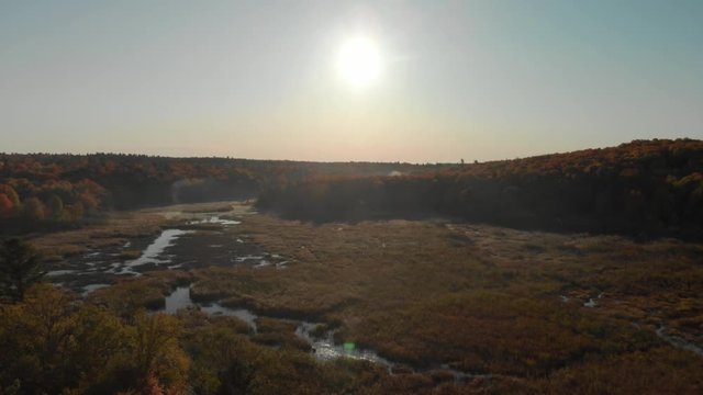 Rising Cinematic Drone Footage Over a Cleared Area with Water in Gatineau Park, Quebec, Canada with Mist at Sunrise.