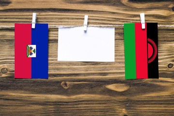 Hanging flags of Haiti and Malawi attached to rope with clothes pins with copy space on white note...