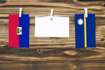 Hanging flags of Haiti and Nauru attached to rope with clothes pins with copy space on white note...