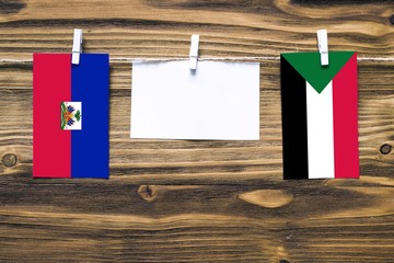 Hanging flags of Haiti and Sudan attached to rope with clothes pins with copy space on white note...
