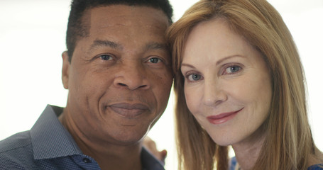 Close up portrait of married senior couple smiling by window