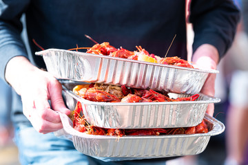 New Orleans, Louisiana city with people by restaurant carrying seafood lobsters crawfish holding stack of many trays