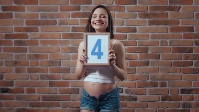 Transformation of pregnant woman's body during pregnancy. Fourth month, second trimester. Waist line change. Nine month before baby is born. Monthly changes, future mother posing in front of camera