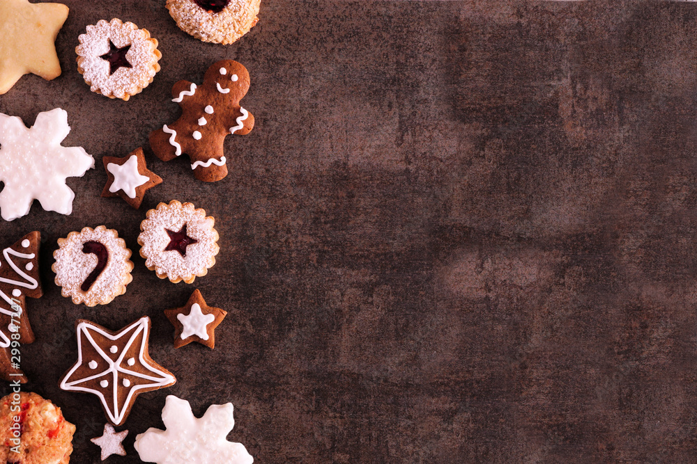 Poster selection of christmas cookies and sweets. above view side border over a dark stone background with 