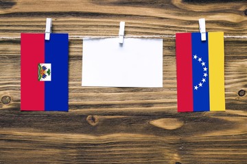 Hanging flags of Haiti and Venezuela attached to rope with clothes pins with copy space on white...