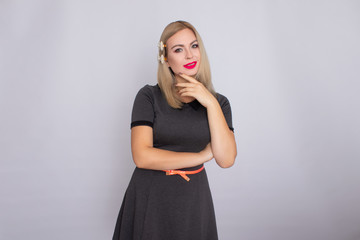 Attractive blonde beauty in grey dress posing on white background