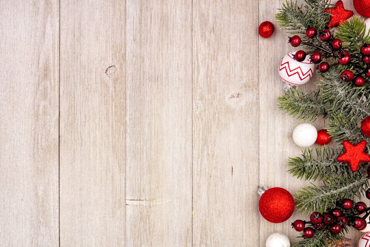 Christmas side border with red and white ornaments and branches. Above view on a gray wood background with copy space.