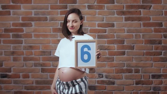 Transformation of pregnant woman's body during pregnancy. Sixth month, second trimester. Waist line change. Nine month before baby is born. Monthly changes, future mother posing in front of camera