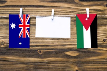 Hanging flags of Heard and Mcdonald Islands and Jordan attached to rope with clothes pins with copy space on white note paper on wooden background.Diplomatic relations between countries.