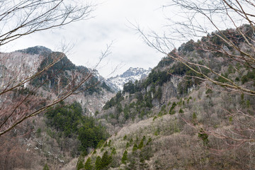 Fototapeta na wymiar Mountain peak low angle view with snow in Okuhida Shinhotaka Ropeway in Gifu Prefecture, Japan park with cloudy sky on spring day