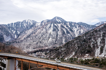 Takayama, Japan aerial view of bridge and car on road in early spring in Gifu Prefecture Okuhida Villages near Shinhotaka Ropeway