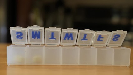 Putting vitamins into weekly pill organizer. Filling pharmaceutical 7 day organizer with daily dose of medication.