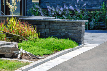 A seat wall adds an architectural element to this contemporary driveway and landscaping.