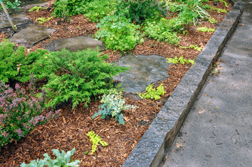 Beautiful natural stone edging acts as a retaining wall in this small urban front garden.