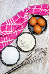 INGREDIENTS AND KITCHEN UTENSILS TO COOK PASTRY. BATTERY, FLOUR, SUGAR, EGGS NEXT TO KITCHEN CLOTH