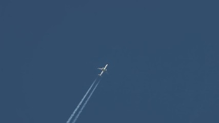 Plane at cruising altitude contrail against blue sky