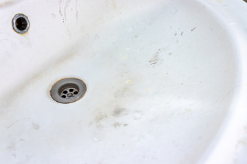 Old dirty washbasin with rust stains, limescale and soap stains in the bathroom