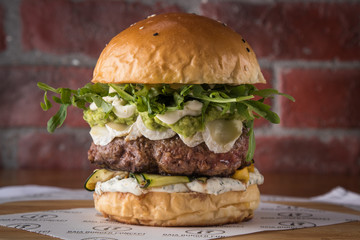 Burger, sandwich, meat, filler, rucola, sauce, bread with a cutlet, American cuisine. Traditional beautiful burger, ingredients and burger details. Food photo