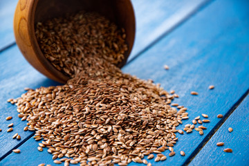 Flax seeds in an old wooden glass. Against the background of blue boards.