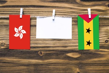 Hanging flags of Hong Kong and Sao Tome And Principe attached to rope with clothes pins with copy...