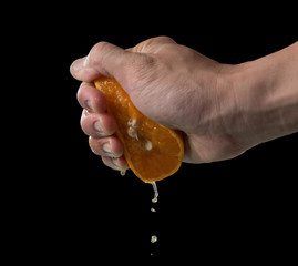 Hand squeeze orange slice with orange juice on black background