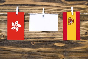 Hanging flags of Hong Kong and Spain attached to rope with clothes pins with copy space on white...