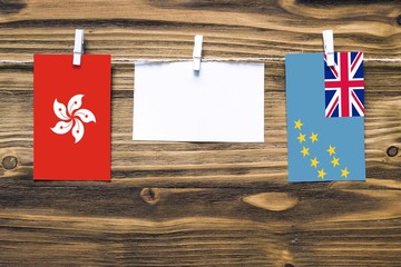 Hanging flags of Hong Kong and Tuvalu attached to rope with clothes pins with copy space on white...