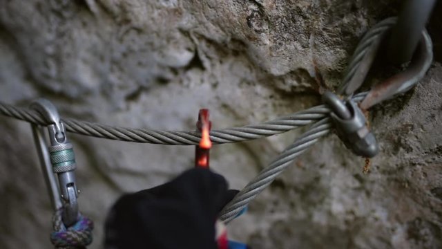 Close-up of cropped hands checking carabiners hanging on rope during rock climbing - Alpes-Maritimes, France