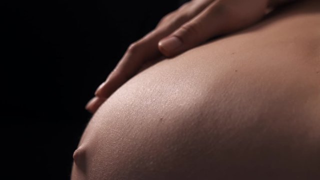 Close-up of pregnant woman with baby moving and kicking inside belly, future mother carefully touch tummy and playing with her baby. Last trimester of pregnancy