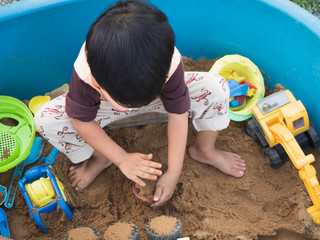 Asian child boy playing car truck toy and sand in sandbox with happy face outdoor with rural...