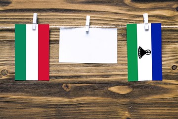 Hanging flags of Hungary and Lesotho attached to rope with clothes pins with copy space on white...