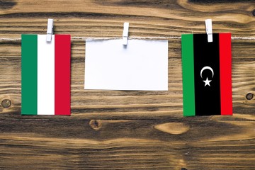 Hanging flags of Hungary and Libya attached to rope with clothes pins with copy space on white note...