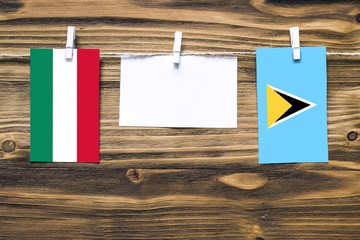 Hanging flags of Hungary and Saint Lucia attached to rope with clothes pins with copy space on white note paper on wooden background.Diplomatic relations between countries.