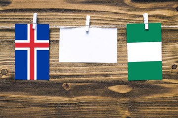 Hanging flags of Iceland and Nigeria attached to rope with clothes pins with copy space on white...