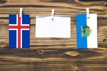 Hanging flags of Iceland and San Marino attached to rope with clothes pins with copy space on white...