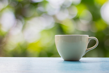 Close up coffee cup on blue wooden table with nature on background