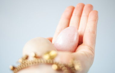 woman holding in hand a vaginal (yoni) egg. Rose quartz crystal jade egg. Copy space