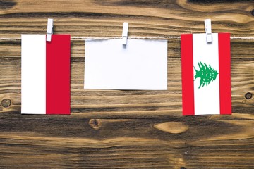 Hanging flags of Indonesia and Lebanon attached to rope with clothes pins with copy space on white note paper on wooden background.Diplomatic relations between countries.