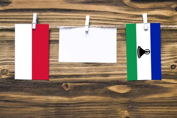 Hanging flags of Indonesia and Lesotho attached to rope with clothes pins with copy space on white...