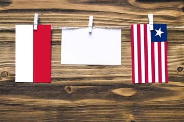 Hanging flags of Indonesia and Liberia attached to rope with clothes pins with copy space on white note paper on wooden background.Diplomatic relations between countries.