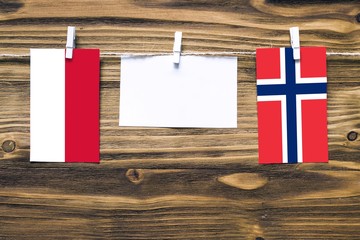 Hanging flags of Indonesia and Norway attached to rope with clothes pins with copy space on white...