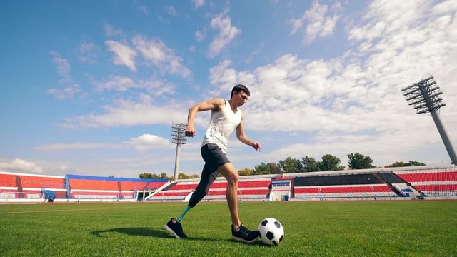 Disabled footballer is running with a ball in slow motion