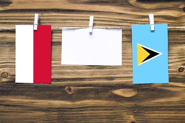 Hanging flags of Indonesia and Saint Lucia attached to rope with clothes pins with copy space on white note paper on wooden background.Diplomatic relations between countries.