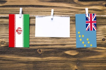 Hanging flags of Iran and Tuvalu attached to rope with clothes pins with copy space on white note...