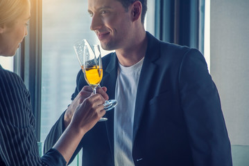  Couples, co-workers, business men, wearing suits, talking to business women, both holding white glasses, standing at the party to greet at bar