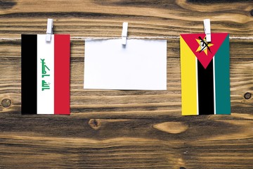 Hanging flags of Iraq and Mozambique attached to rope with clothes pins with copy space on white...