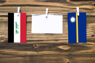 Hanging flags of Iraq and Nauru attached to rope with clothes pins with copy space on white note...